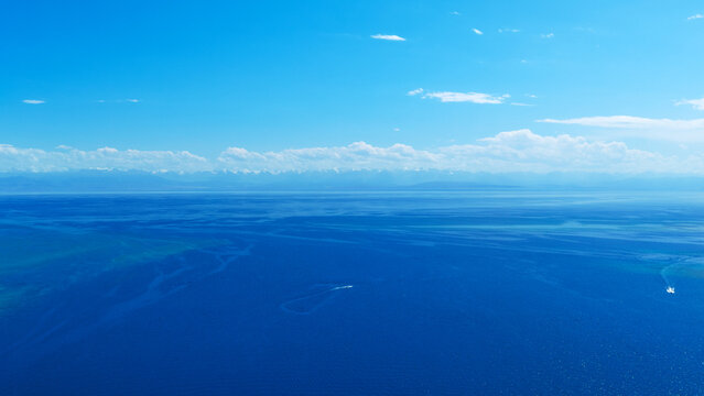 Aerial view of boats on vast blue ocean with mountains