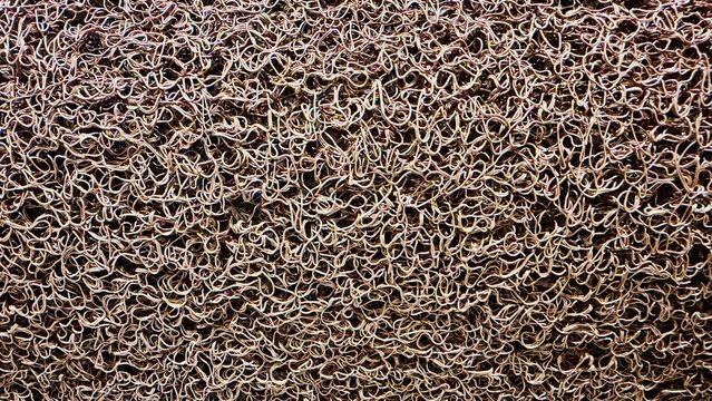 A close-up view of a brown plastic floor mat featuring a dense interlocking structure and textured surface.