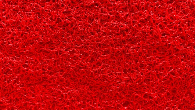 A close-up view of a red plastic floor mat featuring a dense interlocking structure and textured surface.