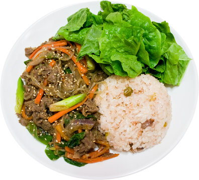 Beef bulgogi with rice and lettuce on round white plate isolated on transparent background, PNG, Korean marinated beef dish with sweet and savory flavor.