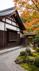 Fototapeta premium Vertical photo of a traditional Japanese garden in autumn. Historic building exterior with wooden gate and colorful maple leaves