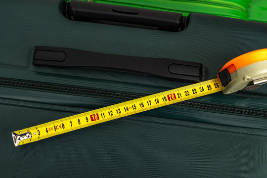 Careful checking of suitcase dimensions at the airport, measuring luggage dimensions, exceeding the weight limit, additional fee for excess luggage, euro banknotes placed on a travel suitcase,