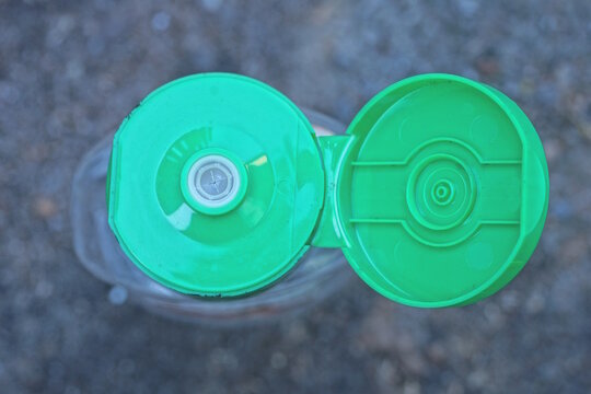 one green plastic open cork on a transparent bottle on a gray background