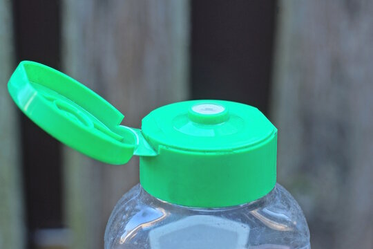 one green plastic open cork on a transparent bottle on a gray background