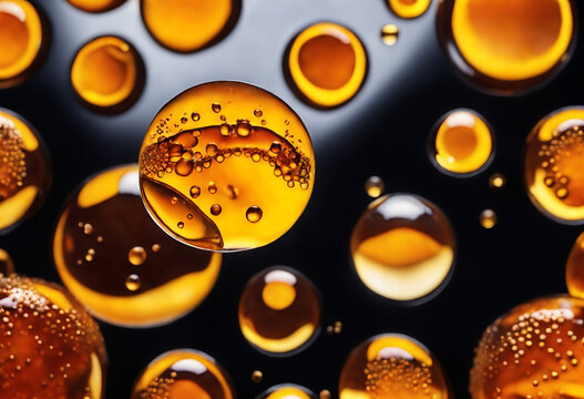 Amber liquid droplets, containing small bubbles, float on a dark surface. Many shiny, golden spheres, filled with microbubbles, are visible.