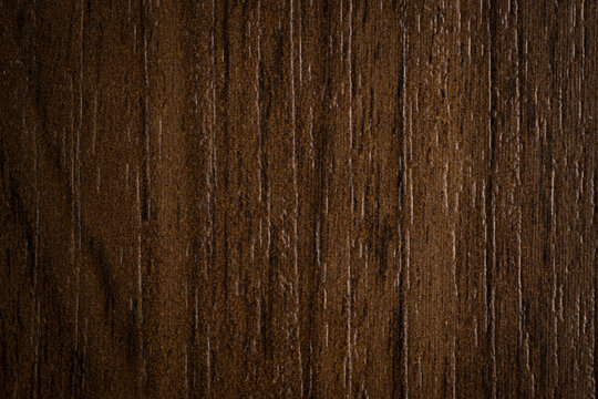 Close-up of dark brown wood grain texture, HPL laminate surface with vertical timber pattern, professional furniture finish background for interior design and architectural visualization.