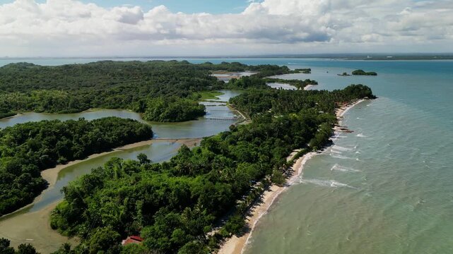 Aerial flyover of a tropical coastline with mangrove forest, sandy shoreline, and ocean waves in Buenavista, Guimaras, Philippines during daytime