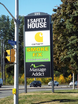Nepean, Ontario, Canada &ndash; July 28, 2025: A roadside directory sign for 595 West Hunt Club Road lists "The Safety House, Carhartt, Smoke FX, and Massage Addict."