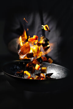 Dramatic flambe of vegetables in dark setting background