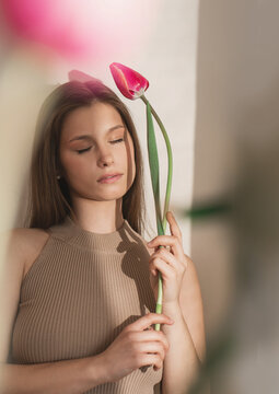 artistic female portrait with closed eyes holding single tulip soft light natural beauty minimal aesthetic calm mood tender expression feminine elegance floral symbolism dreamy fine art style