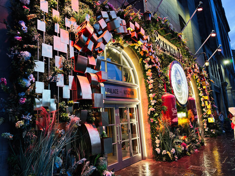 Festive floral Brewhemia storefront and illuminated entrance of Palace Kitchen in Edinburgh, Scotland, UK at night with decorative archway and neon lights