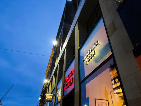 Franco Manca pizza restaurant storefront on a busy Edinburgh, Scotland, UK street at dusk with neon signs, glass windows and modern city architecture