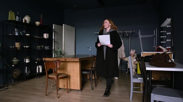 Professional real estate agent guiding a young mother and her little daughter through a spacious, contemporary apartment, discussing the property details and showing them the modern kitchen