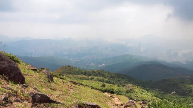 View from the top of a mountain with alpine meadows to the valley of Hong Kong city in fog clouds and smog