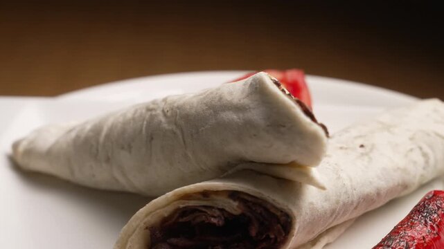 Traditional Turkish meat doner kebab wraps rotating with tomato and grilled pepper on a white plate, fa01