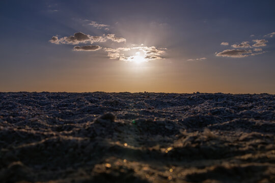 Sunlight through clouds over rippled sand at the beach