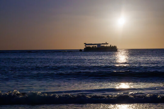

Ship at sunset over the ocean with gentle surf in the foreground