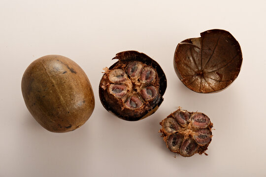 Whole and halved luo han guo fruits with detailed cross-section showing seeds and outer shell on white background