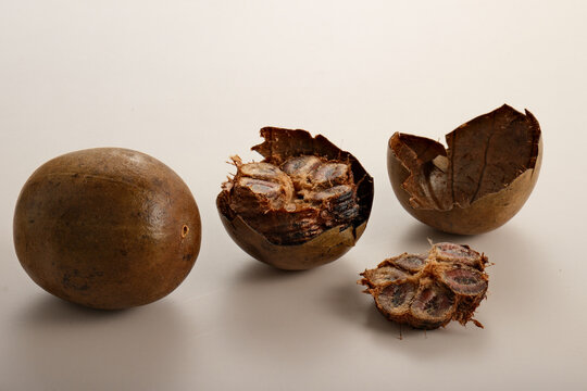 Whole and halved luo han guo fruits with detailed cross-section showing seeds and outer shell on white background