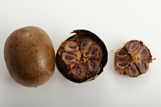 Whole and halved luo han guo fruits with detailed cross-section showing seeds and outer shell on white background