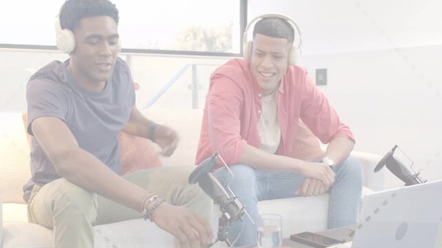 Left man reaching for microphone, starting podcast test while both adjusting headphones and smiling
