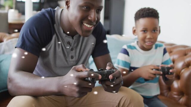 Dad and son on sofa, holding pads, white particles orbiting hands, fist bumping after gaming win