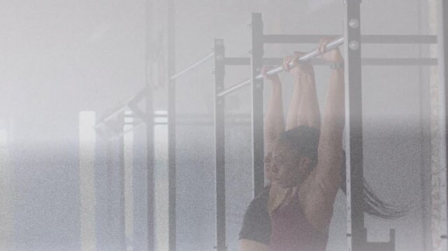 Two women entering right side, gripping pull-up bar in gym and performing hanging pulls for fitness