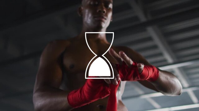 Male boxer preparing for sports, wrapping red wraps while hourglass overlay partly hiding hands