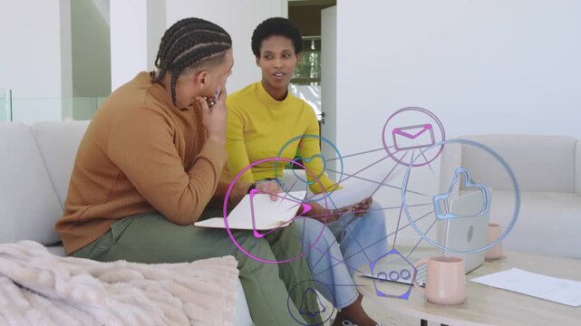 Woman explaining while man noting, exchanging docs sparking chat icons over laptop for business