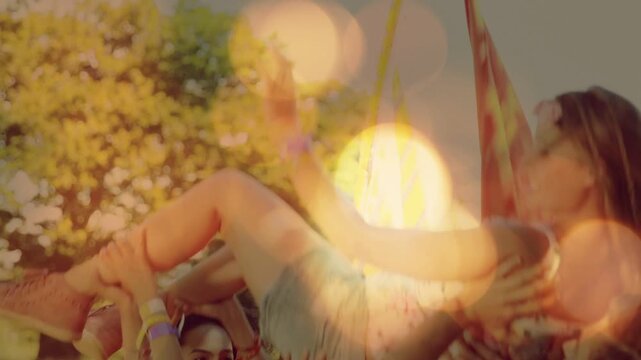 Festival crowd lifting woman lying flat hands initiating crowd-surf right by red flag celebrating