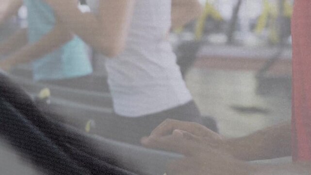 Man pressing treadmill console and yellow safety clip, female runners maintaining pace for workout