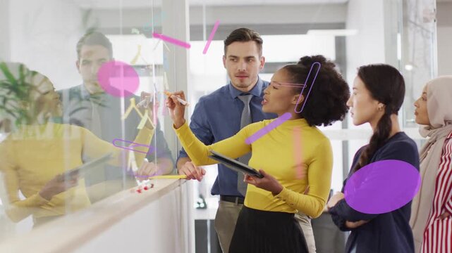 Vertical video: Stepping forward lead in yellow top drawing on glass using tablet for brainstorming