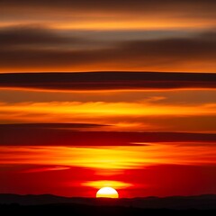 Obraz premium Vibrant orange and red sunset over a silhouetted mountain range