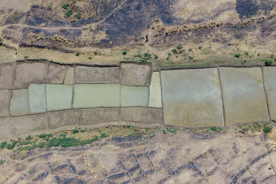 Aerial view of the patchwork fields, reflecting the sky, contrasting with the earth tones of the arid landscape, Argungu, Kebbi, Nigeria.