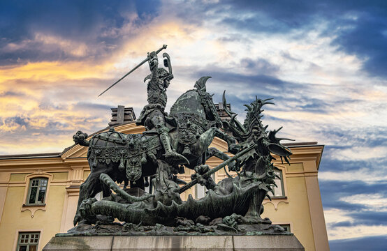 The bronze sculpture of Saint George and the Dragon stands majestically against a sunset sky at Kopmantorget in the Gamla Stan district of Stockholm, Sweden.