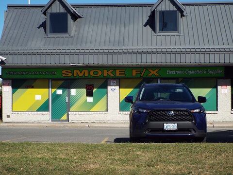 Nepean, Ontario, Canada &ndash; July 28, 2025: A blue SUV is parked in front of the "Smoke F/X" electronic cigarettes and supplies storefront on a sunny day at 595 W Hunt Club Rd.