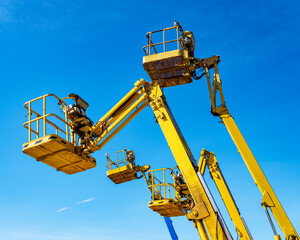 Cherry pickers on a blue sky background © ceebeestock