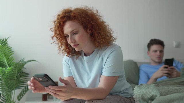 Distracted couple using smart phones in bed ignoring each other