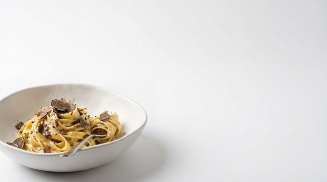 Gourmet tagliatelle pasta with sliced black truffles in a white bowl