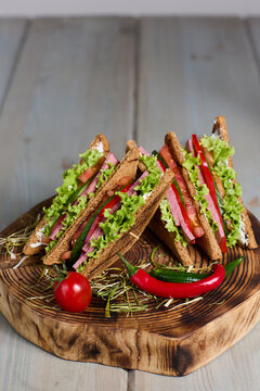 Fresh club sandwich with ham vegetables on rye bread served on rustic wood