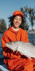 Fototapeta premium Young man smiling while holding large fish on lake boat