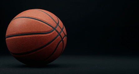 Fototapeta premium A basketball resting on a black background, showcasing its orange color and textured surface