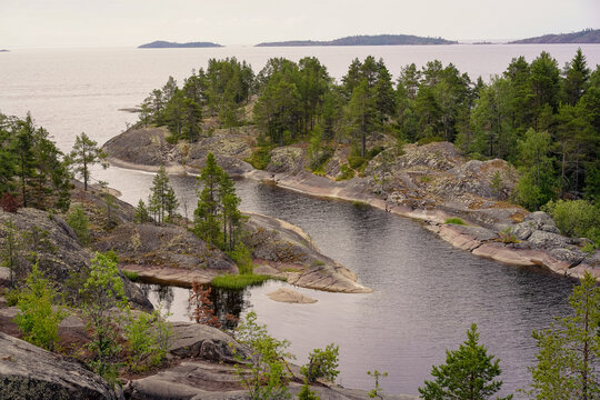Aerial view of a northern archipelago, featuring a narrow water channel winding through rugged granite islands covered in moss, lichen, and dense pine forests. Sortavala, Karelia, skerries, Ladoga