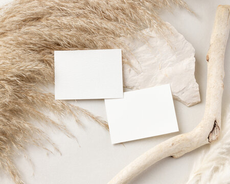 Blank sided cards set mockup on beige stone with driftwood and pampas grass top view, wedding stationery