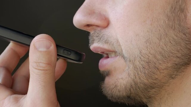 Close up of man speaking to smartphone during voice assistant interaction. Concept of speech recognition, digital communication, everyday AI use and human connection with technology.