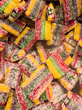 Close-up of rainbow sour candy belts covered in sugar forming a colorful textured candy background.