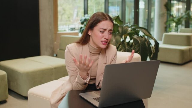 Caucasian young businesswoman girl using laptop notebook typing browsing, loses becoming surprised sudden lottery results, bad news fortune loss fail in modern office lobby. Lady sitting in hotel hall