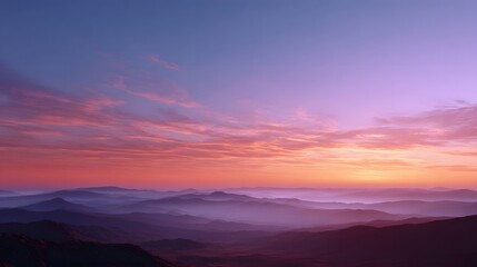 Fototapeta premium Vibrant dawn colors spread across receding layers of misty mountain ranges