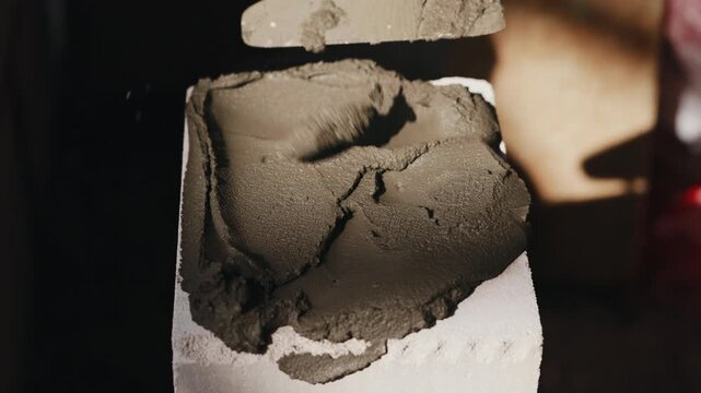Applying mortar inside aerated concrete block with trowel close up