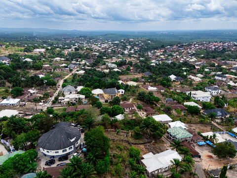 Aerial view of a residential landscape, with varied rooftops peeking through abundant green trees under an overcast sky, Asaga, Abia, Nigeria.